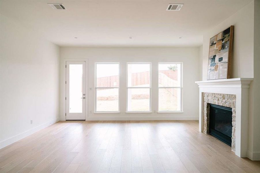 Unfurnished living room featuring light hardwood / wood-style floors and a stone fireplace