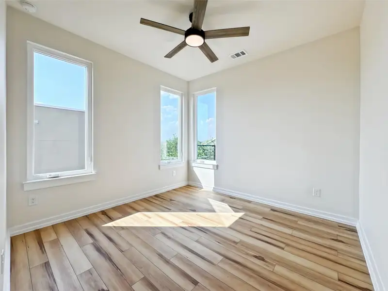 Spare room featuring plenty of natural light, light wood-type flooring, and ceiling fan