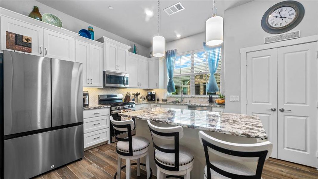 Kitchen featuring tasteful backsplash, stainless steel appliances, dark wood-type flooring, a kitchen island, and white cabinets