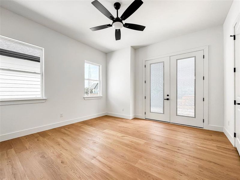 Empty room featuring light wood-style floors, french doors, baseboards, and a ceiling fan
