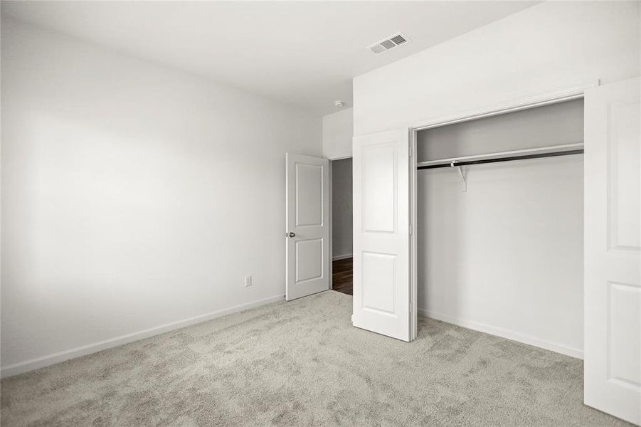 Secondary bedroom with soft neutral tones, walk-in closet entry, and comfortable proportions.