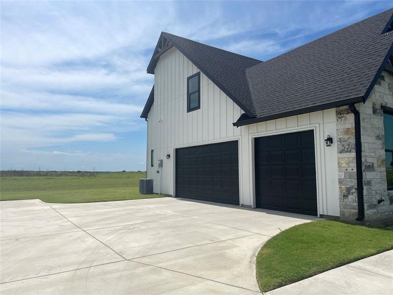 View of home's exterior with roof with shingles, stone siding, board and batten siding, and concrete driveway View of home's exterior with roof with shingles, stone siding, board and batten siding, and concrete driveway