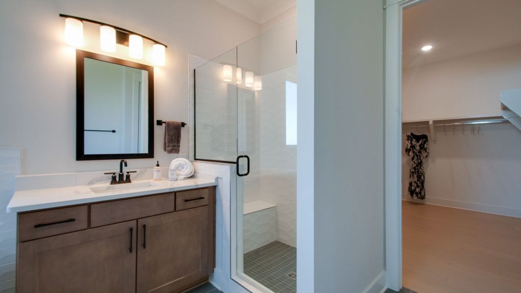 Bathroom vanity with glass shower enclosure and entry to primary suite closet Bathroom vanity with glass shower enclosure and entry to primary suite closet