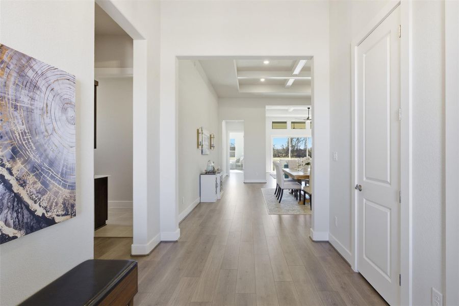 Corridor with light wood-style floors, coffered ceiling, and recessed lighting