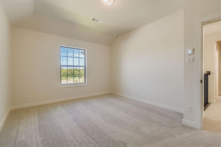 Unfurnished room featuring light colored carpet and vaulted ceiling