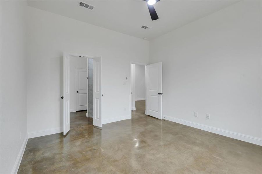 Unfurnished bedroom with concrete flooring and ceiling fan