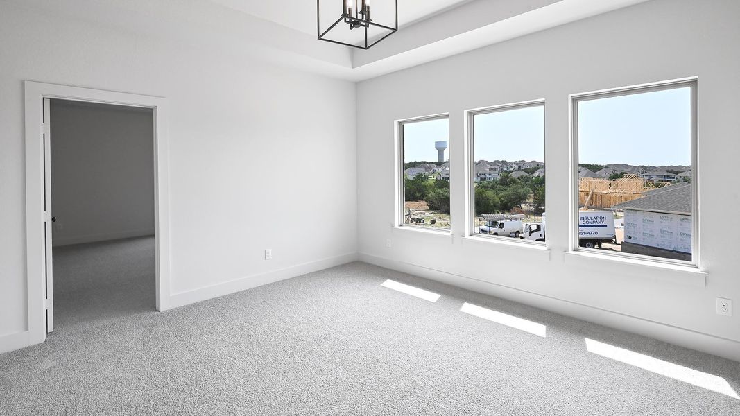 Carpeted spare room featuring a chandelier and baseboards