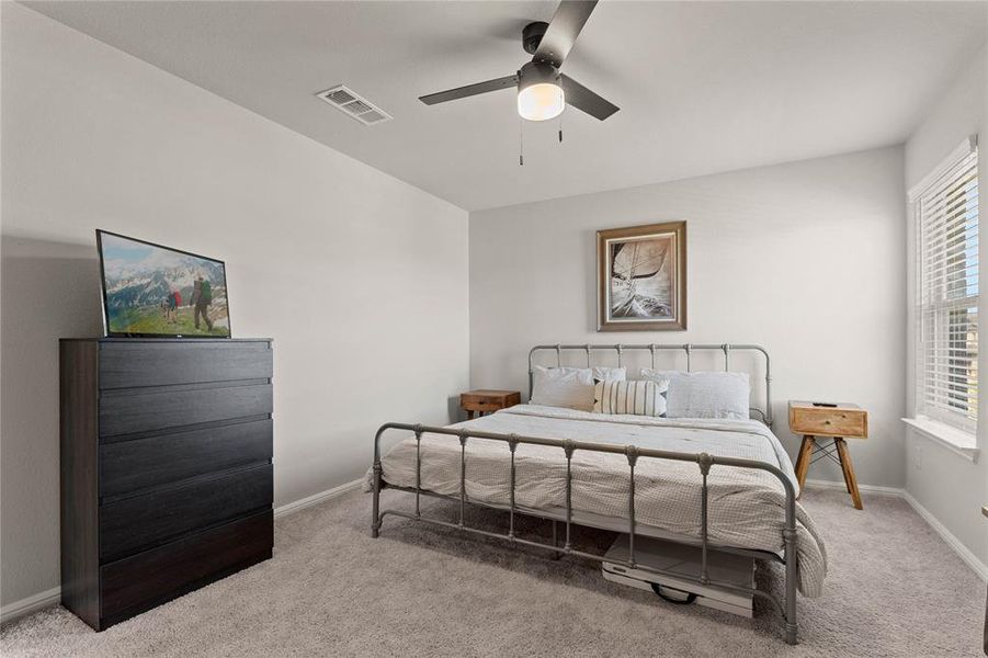 Upstairs carpeted bedroom featuring ceiling fan, baseboards, and large window