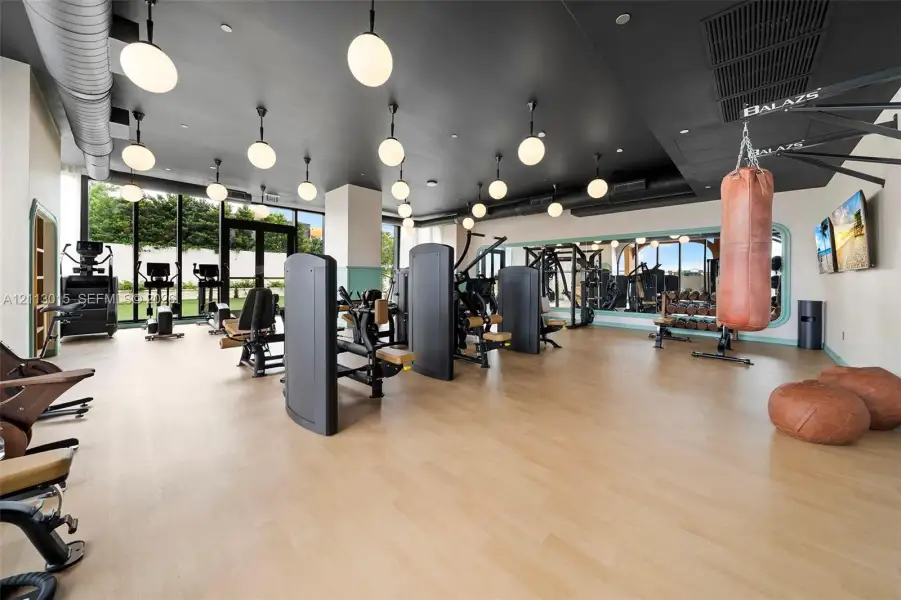 Fitness center featuring wood-finish flooring, floor-to-ceiling windows, recessed and pendant lighting, and a full-length wall mirror
