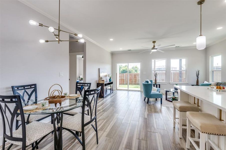 Dining area featuring ceiling fan with notable chandelier, crown molding, and light hardwood / wood-style floors