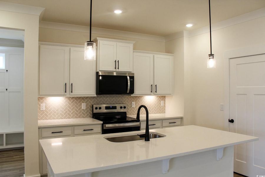 Kitchen with white cabinets, tasteful backsplash, appliances with stainless steel finishes, crown molding, and recessed lighting