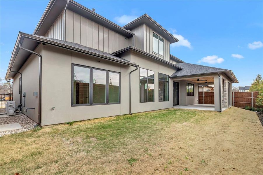 Rear view of house with a fenced backyard, a patio, ceiling fan, stucco siding, and board and batten siding Rear view of house with a fenced backyard, a patio, ceiling fan, stucco siding, and board and batten siding