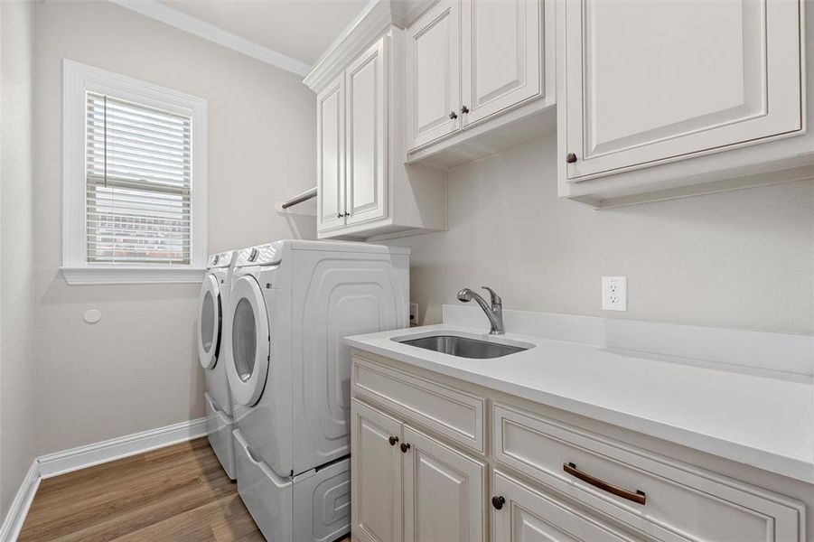 Utility room with built-in cabinetry, quartz counters, and a sink. Utility room with built-in cabinetry, quartz counters, and a sink.