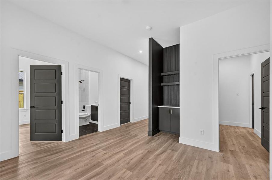 Wood-finish flooring throughout, complemented by white walls and modern dark panel doors Wood-finish flooring throughout, complemented by white walls and modern dark panel doors