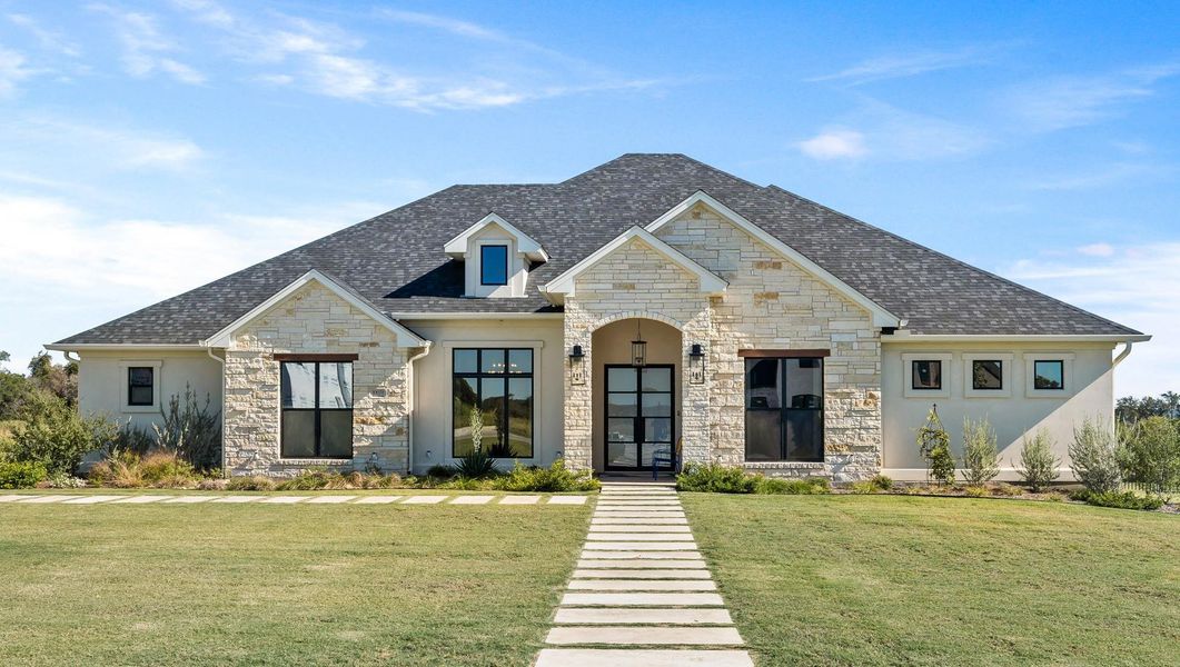 View of front of property with a front yard, stone siding, roof with shingles, and stucco siding