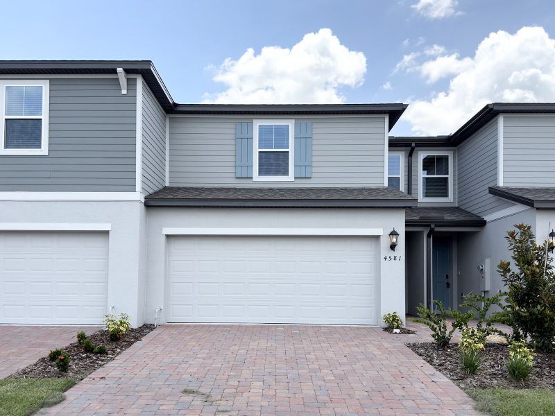 Front exterior of a new home in The Meadow at Crossprairie Townes, St. Cloud, FL, highlighting curb appeal (Image 1). Front exterior of a new home in The Meadow at Crossprairie Townes, St. Cloud, FL, highlighting curb appeal (Image 1).