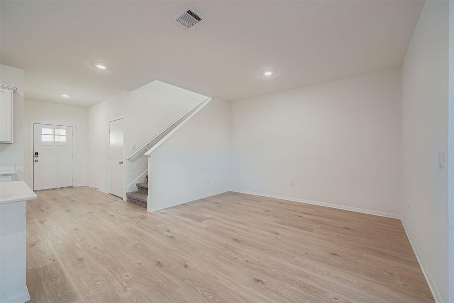 Unfurnished living room featuring light wood-style floors, stairway, and recessed lighting