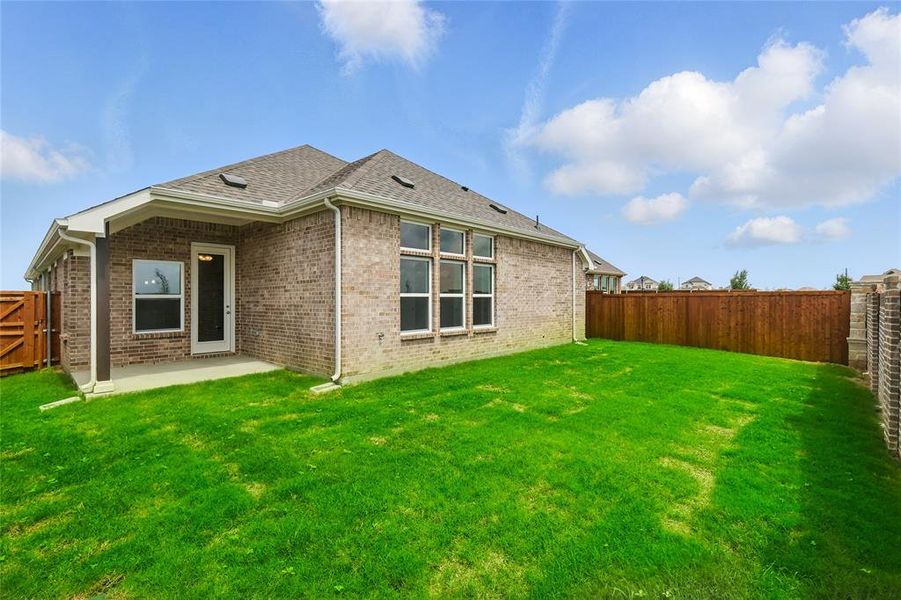 Rear view of house featuring a patio area, brick siding, and roof with shingles
