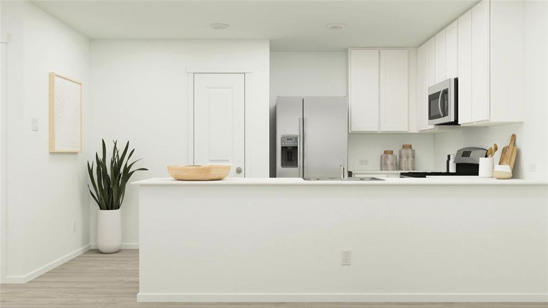 Kitchen with stainless steel appliances, white cabinetry, baseboards, light countertops, and light wood-type flooring