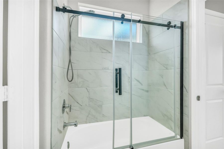 Thoughtful design continues here with a modern shower-tub combo featuring floor-to-ceiling tile and high-quality fixtures.