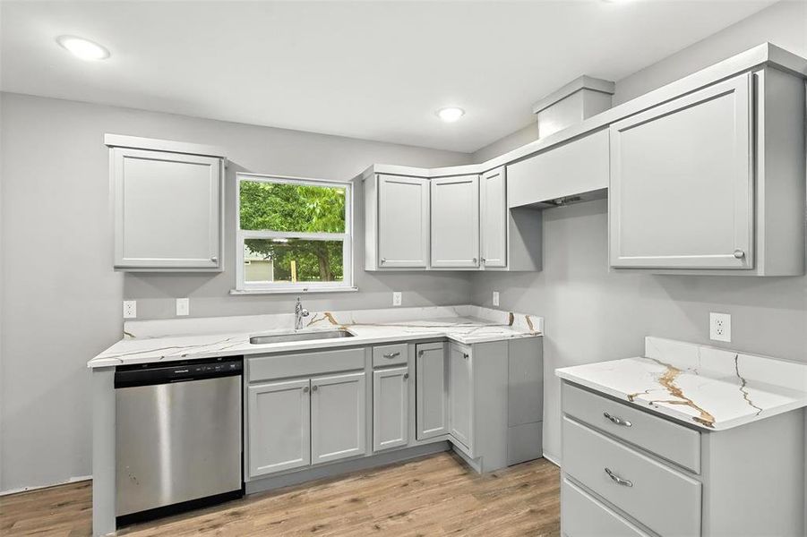 Kitchen featuring gray cabinets, dishwasher, light wood-style floors, light stone counters, and recessed lighting Kitchen featuring gray cabinets, dishwasher, light wood-style floors, light stone counters, and recessed lighting