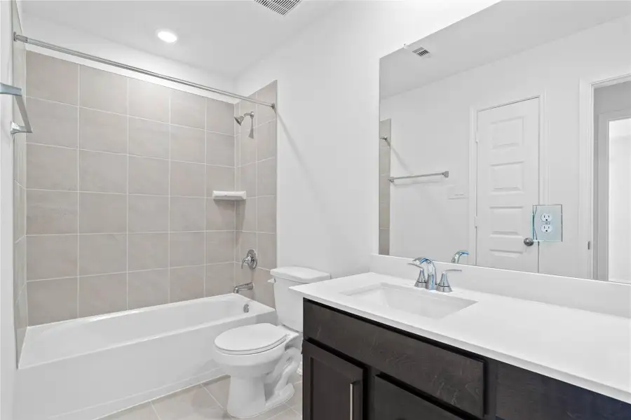 The secondary bathroom showcases tile flooring, a bath/shower combo with tile surround, a vanity with a stunning light countertop, a mirror, sleek fixtures, and contemporary finishes throughout. The secondary bathroom showcases tile flooring, a bath/shower combo with tile surround, a vanity with a stunning light countertop, a mirror, sleek fixtures, and contemporary finishes throughout.