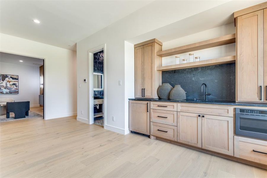 Kitchen with light brown cabinets, sink, oven, and light wood-type flooring