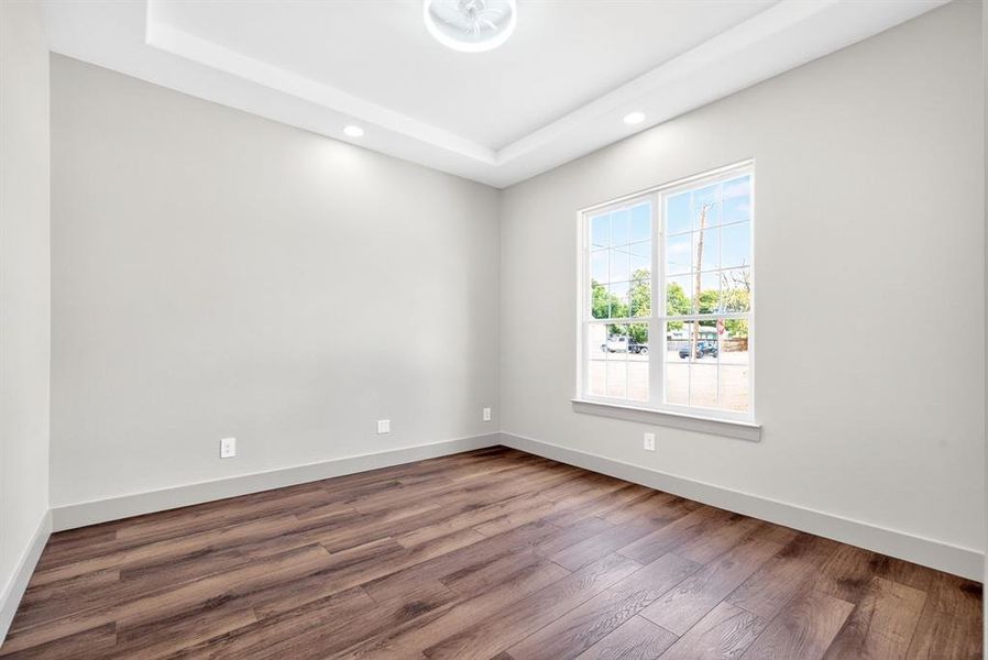 Unfurnished room featuring recessed lighting, wood finished floors, and a tray ceiling Unfurnished room featuring recessed lighting, wood finished floors, and a tray ceiling