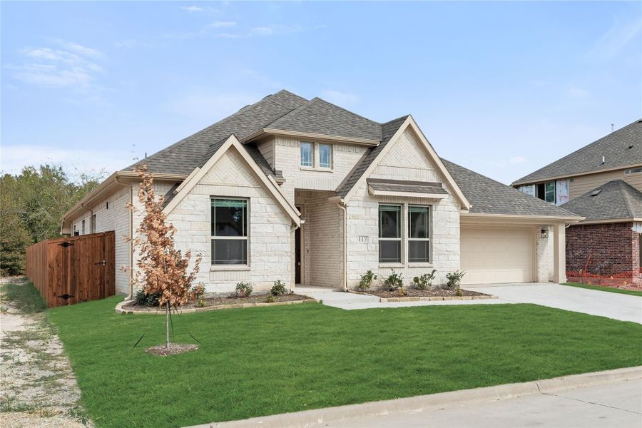 Two-story home with light brick and stone exterior, two-car garage, and green front lawn