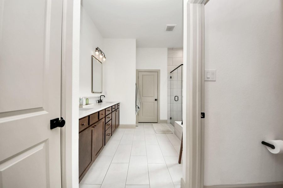 Indulge in the luxury of your primary bathroom, featuring dual sinks, a separate shower, and a relaxing tub for ultimate comfort.