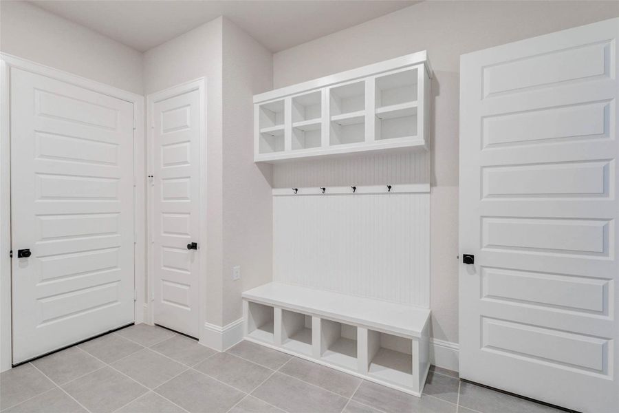 Large MUD drop space features built-in shelving and storage cubbies, a bench, and wall hooks for convenience. The space is bright with neutral tones making it both functional and stylish for everyday use.
