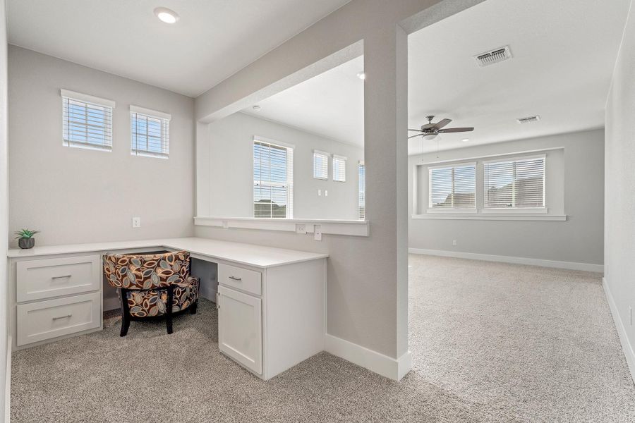 Unfurnished office featuring built in desk, light colored carpet, healthy amount of natural light, a ceiling fan, and recessed lighting Unfurnished office featuring built in desk, light colored carpet, healthy amount of natural light, a ceiling fan, and recessed lighting