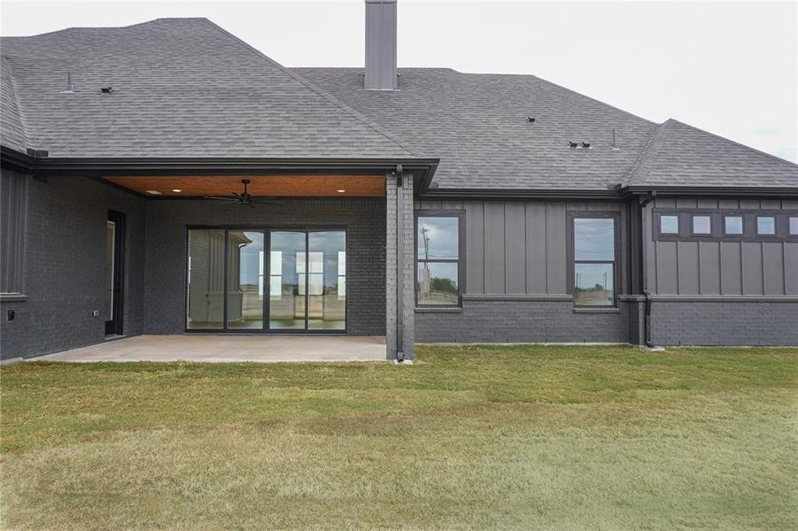 Back of property with ceiling fan, a lawn, and a patio area