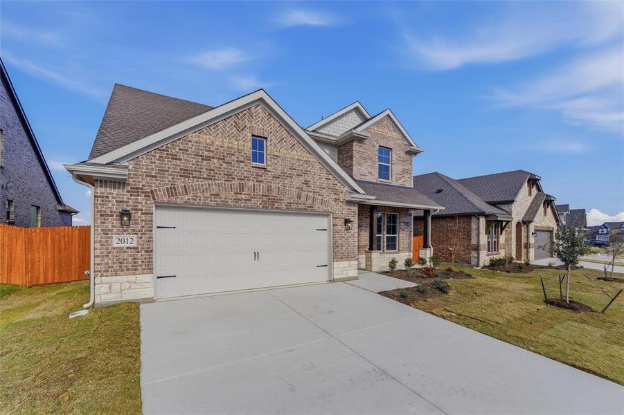 View of front of home featuring brick siding, driveway, a shingled roof, and covered porch