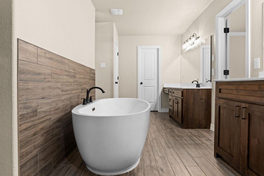 Full bathroom with dual vanities, a soaking tub, and wood-style tile flooring Full bathroom with dual vanities, a soaking tub, and wood-style tile flooring