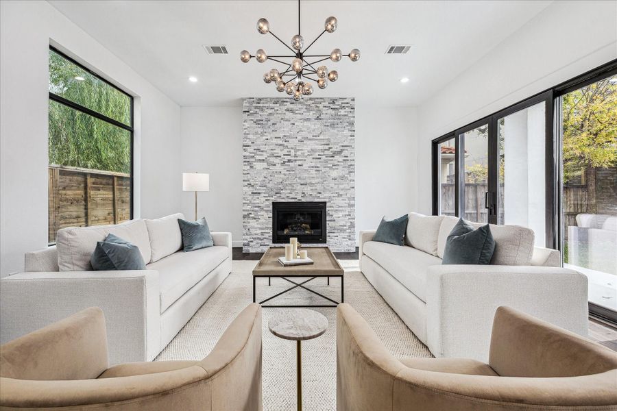 The living room is centered around a stunning gas log fireplace surrounded by stone, creating a warm and inviting focal point while complementing the home’s elegant design.