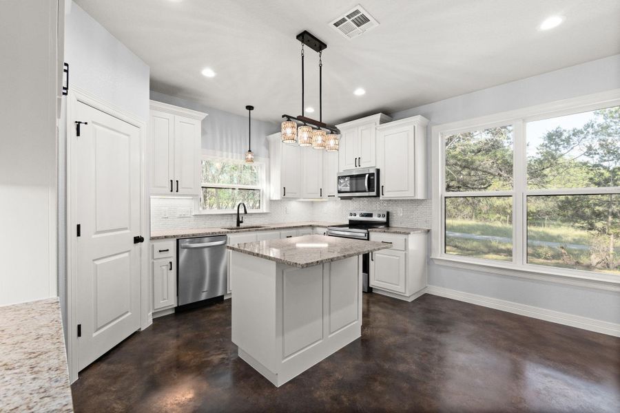 Kitchen featuring tasteful backsplash, concrete floors, white cabinets, and recessed lighting
