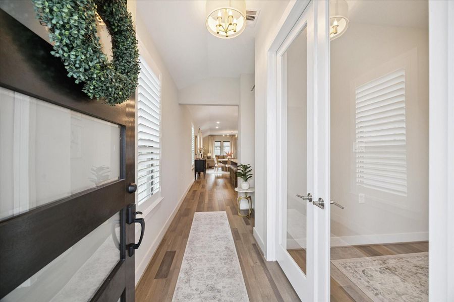Step inside to a bright and elegant foyer lined with wood flooring, plantation shutters, and a view that draws you toward the open living area.