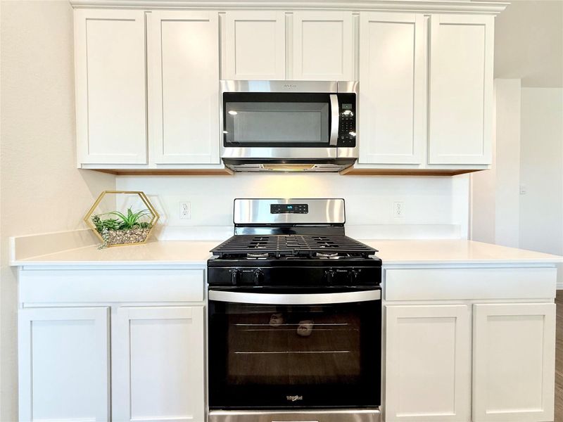 Kitchen with stainless steel appliances, light countertops, and white cabinets Kitchen with stainless steel appliances, light countertops, and white cabinets