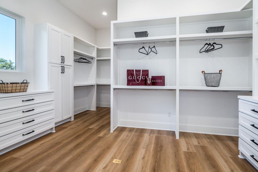 Spacious primary closet featuring built-in shelving for organized storage and easy wardrobe access. Spacious primary closet featuring built-in shelving for organized storage and easy wardrobe access.