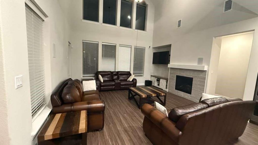 Living area featuring a towering ceiling, dark wood-style floors, and a fireplace