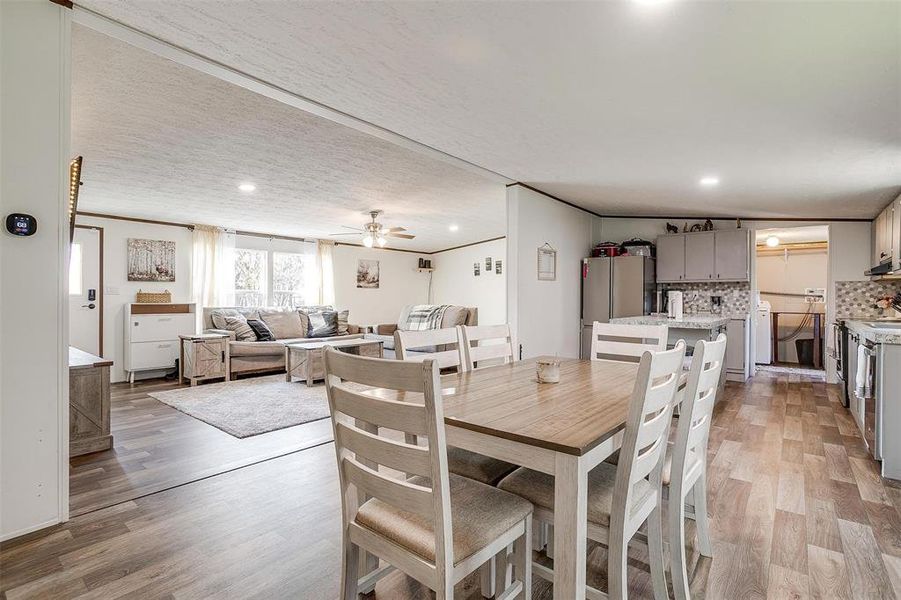 Dining area featuring a textured ceiling, ceiling fan, ornamental molding, and light hardwood / wood-style floors