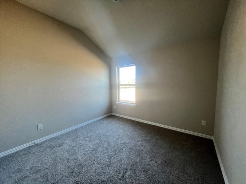 Spare room with vaulted ceiling and carpet floors