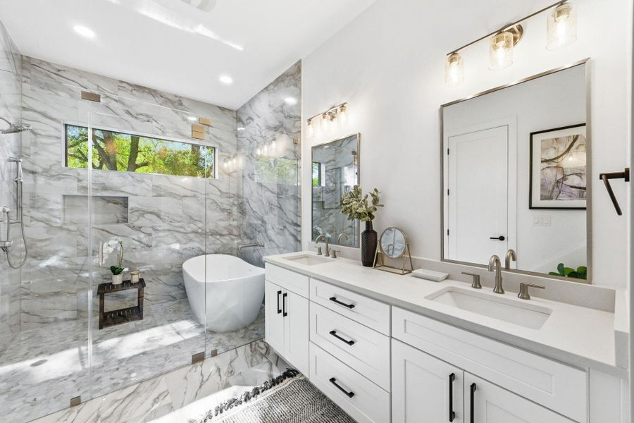 Primary bathroom featuring light marble finish flooring, double vanity, wet room style  soaking tub and shower plus recessed lighting,