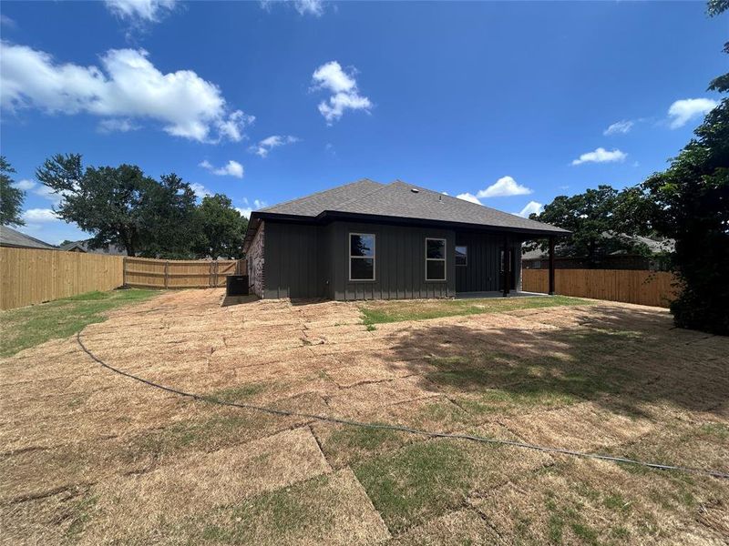 Back of property with board and batten siding, a fenced backyard, and a shingled roof Back of property with board and batten siding, a fenced backyard, and a shingled roof
