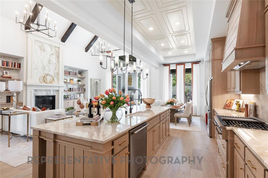 Kitchen featuring custom range hood, beam ceiling, light wood-style floors, a notable chandelier, and appliances with stainless steel finishes Kitchen featuring custom range hood, beam ceiling, light wood-style floors, a notable chandelier, and appliances with stainless steel finishes