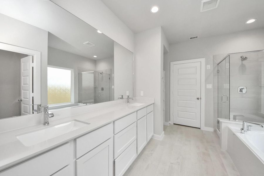Indulge in a spa-like retreat within the confines of this primary bathroom. Delight in a spacious walk-in shower enveloped in stylish tile surround, unwind in a separate garden tub adorned with custom detailing.