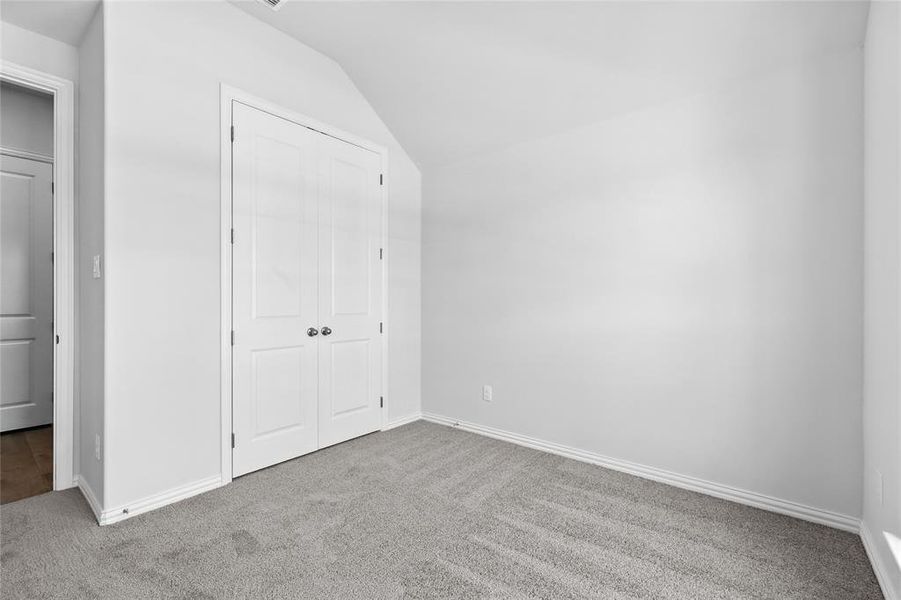 Unfurnished bedroom with lofted ceiling, light carpet, and a closet