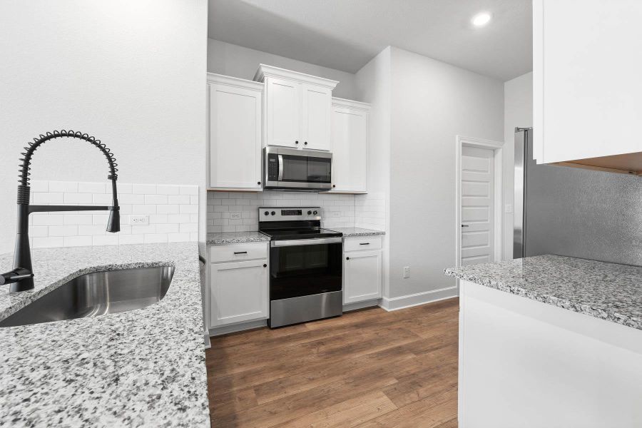 The open layout allows for multiple people to be in the kitchen at once and supplies extra counter and storage space. This well-equipped gourmet kitchen is complete with gorgeous white granite countertops, stainless steel appliances and a large pantry with shelves.