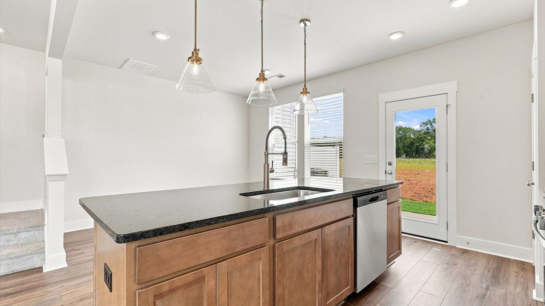 Vibrant and open kitchen centered around a large island with elegant pendant lighting above at Saluda Crossing Vibrant and open kitchen centered around a large island with elegant pendant lighting above at Saluda Crossing